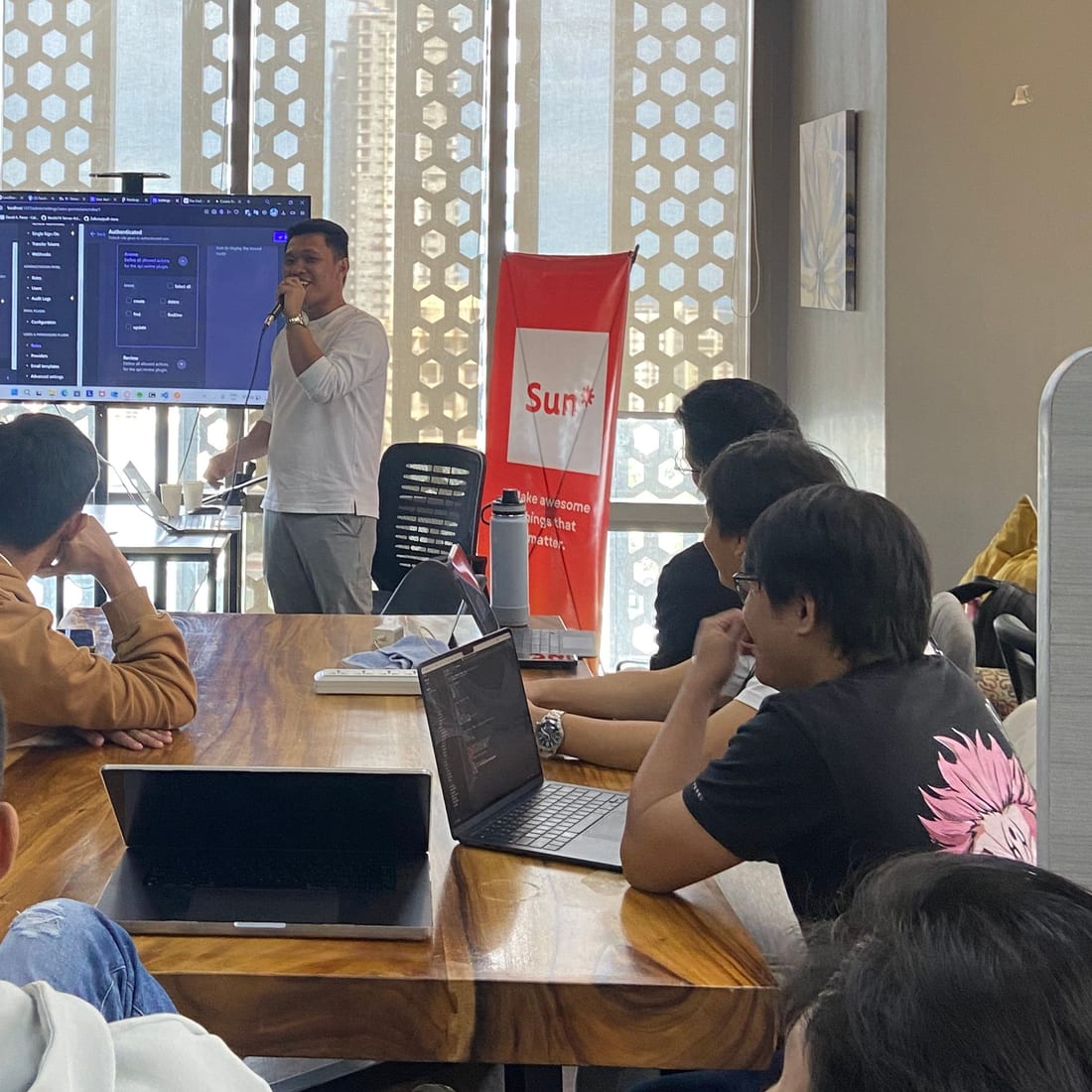 A Sun* Philippines engineer running a hands-on developer workshop, presenting from a wall screen to a room of developers.