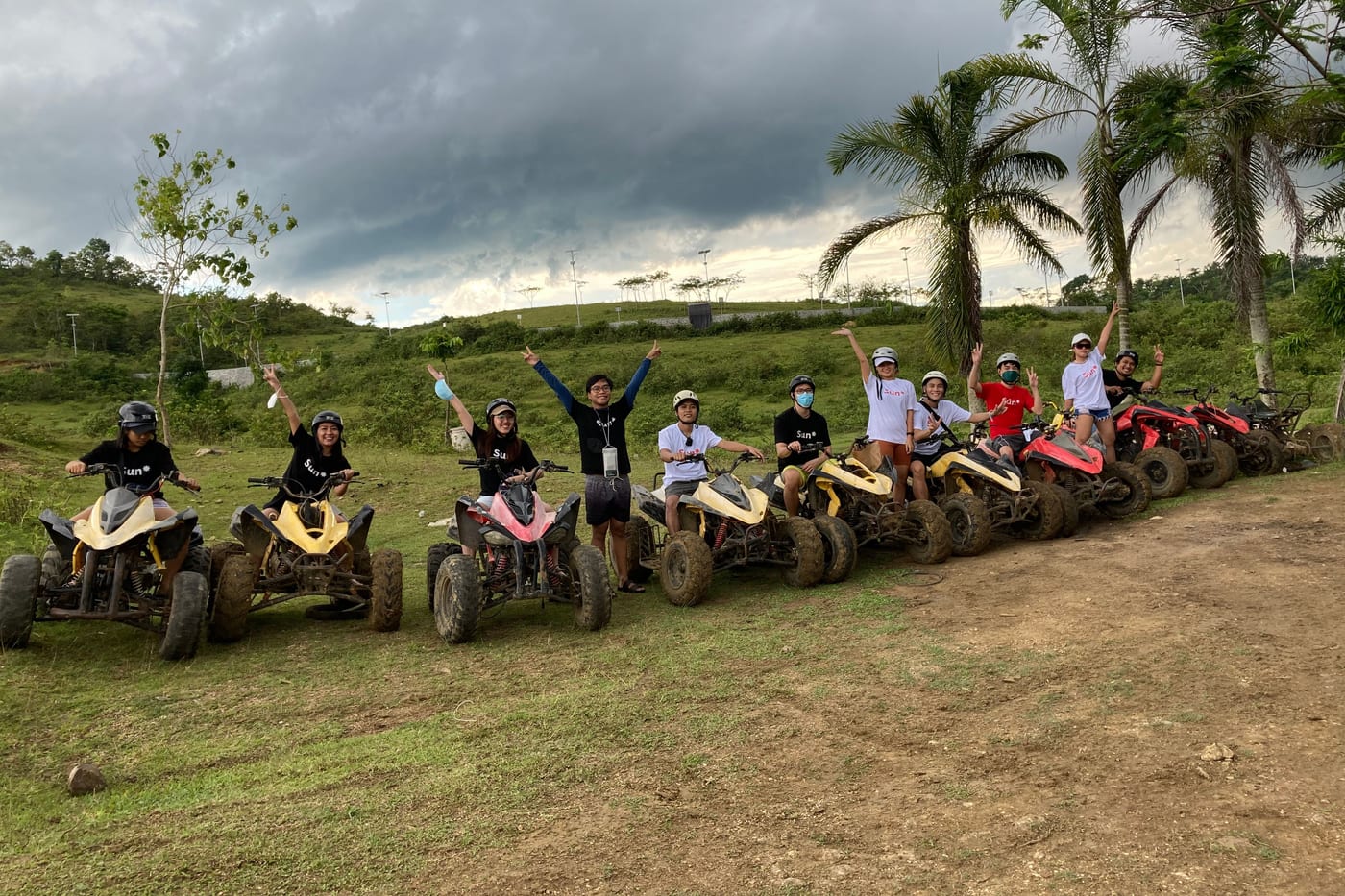 The Sun* Philippines team lined up on ATVs on a hillside trail, arms raised, during a team adventure ride.