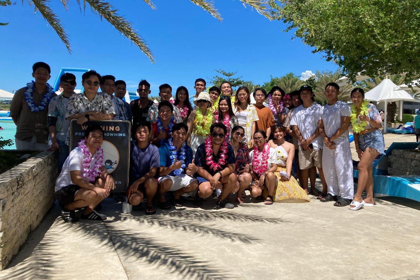 The Sun* Philippines team posing together in leis by the pool during a company outing.