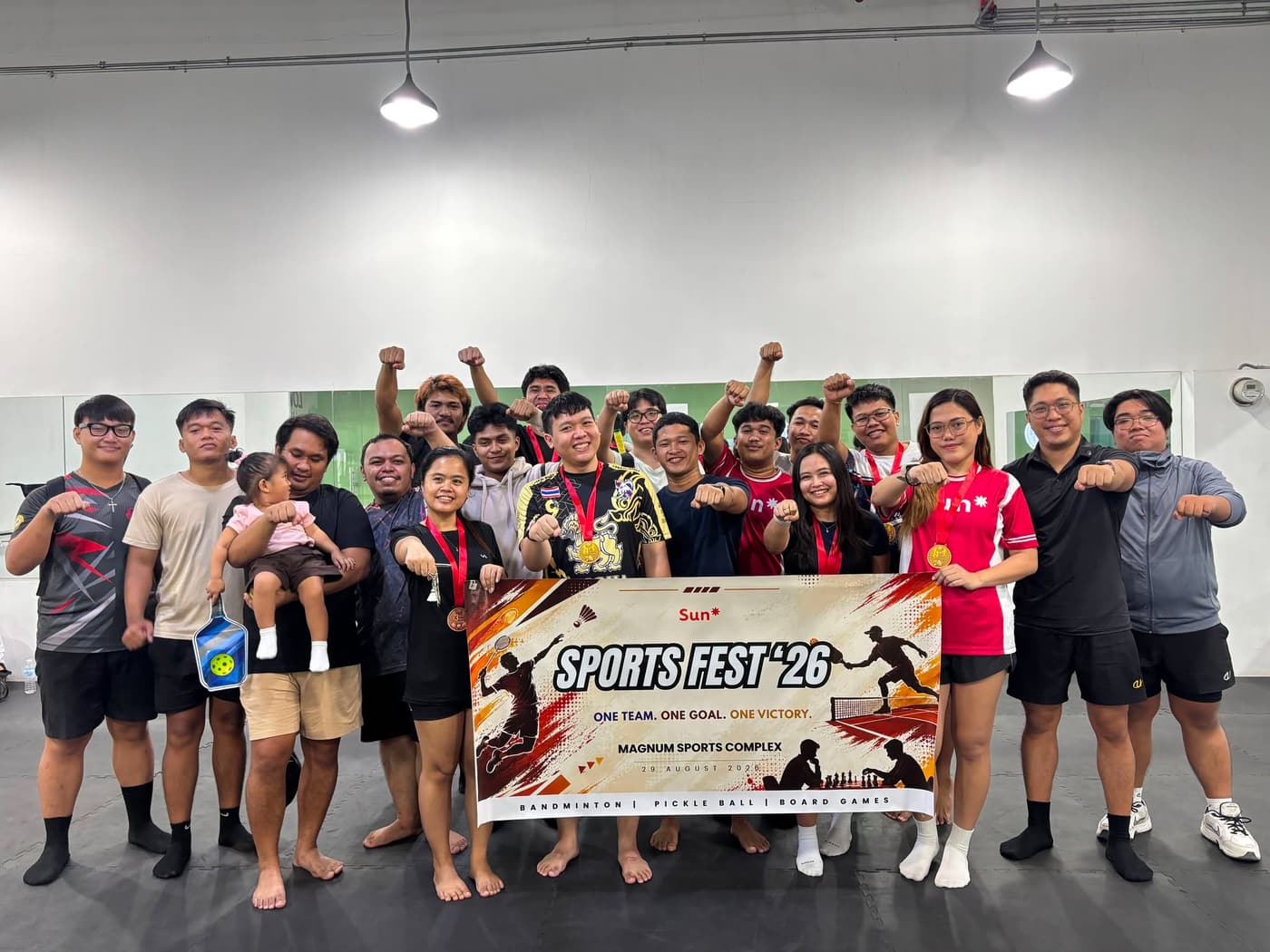 The team posing with medals behind a Sun* Sports Fest '26 banner.