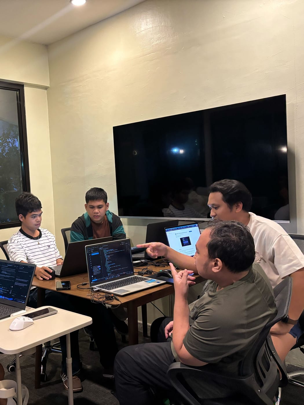 Sun* Philippines engineers huddled around a laptop in the co-working room, one of them pointing at the screen as the group works through the problem.