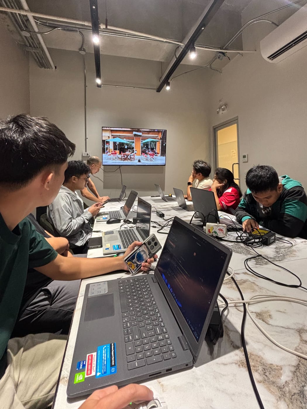 Sun* Philippines engineers heads-down along the long co-working table, laptops open and the wall screen on behind them.