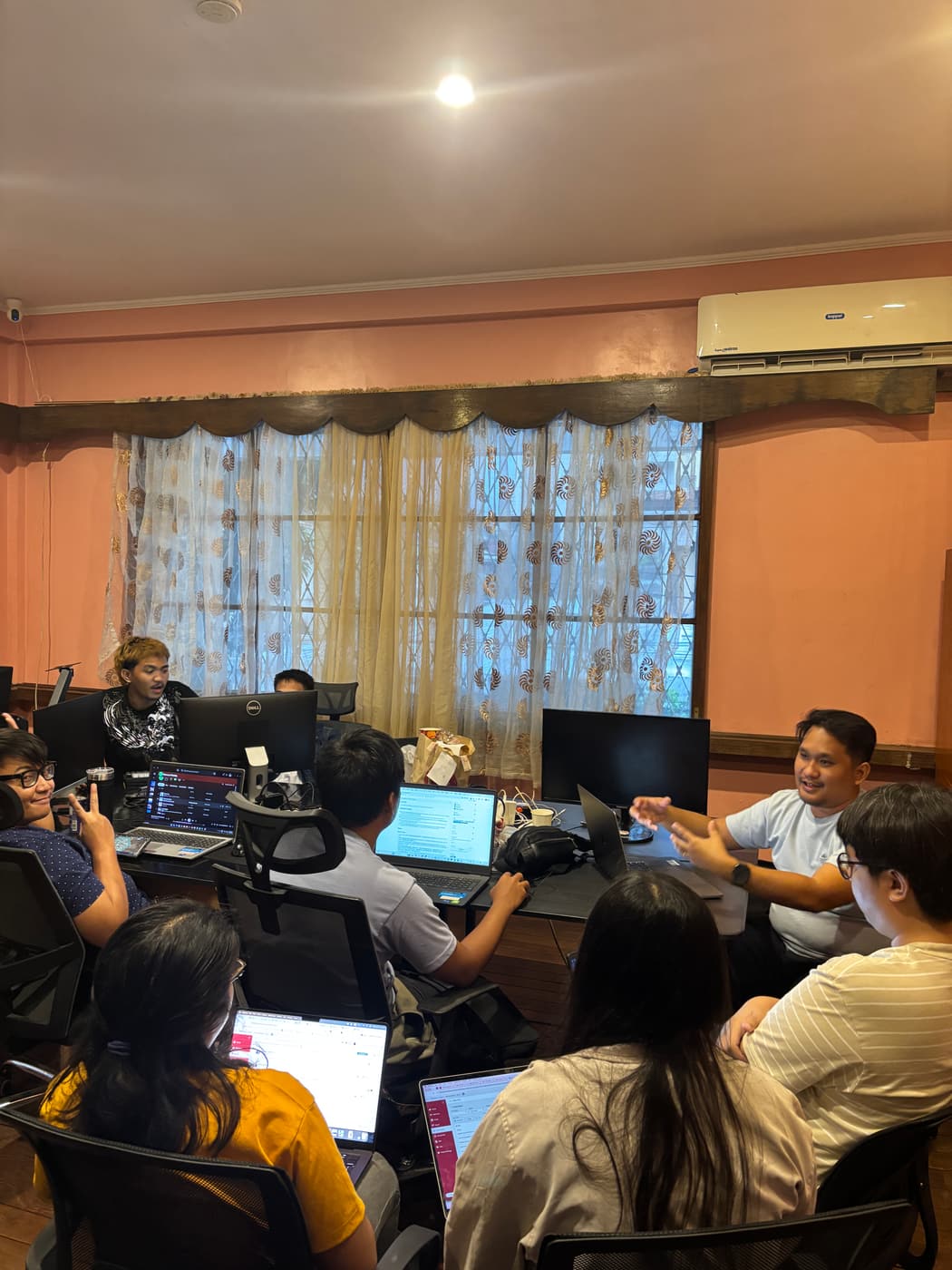 Sun* Philippines team members talking through a problem together, laptops open around the table.