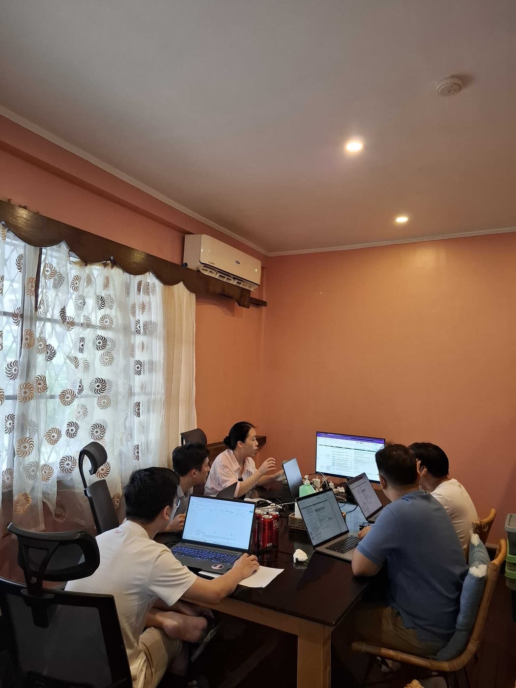 Five Sun* Philippines team members working through a problem together around their laptops.